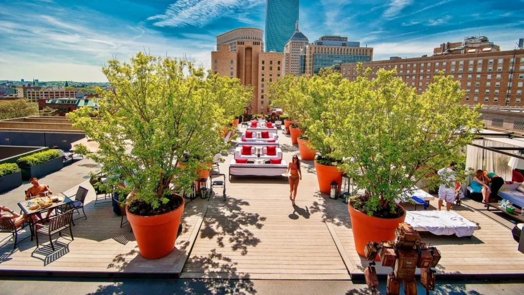 Rooftop bar with wooden flooring and white couches on a sunny Boston day