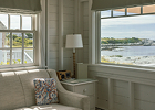 A bright, sunlit room featuring large windows with ocean views and a cushioned window seat.