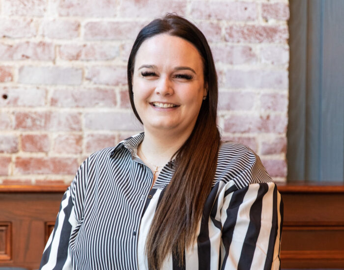Smiling woman with long dark hair in black and white striped shirt