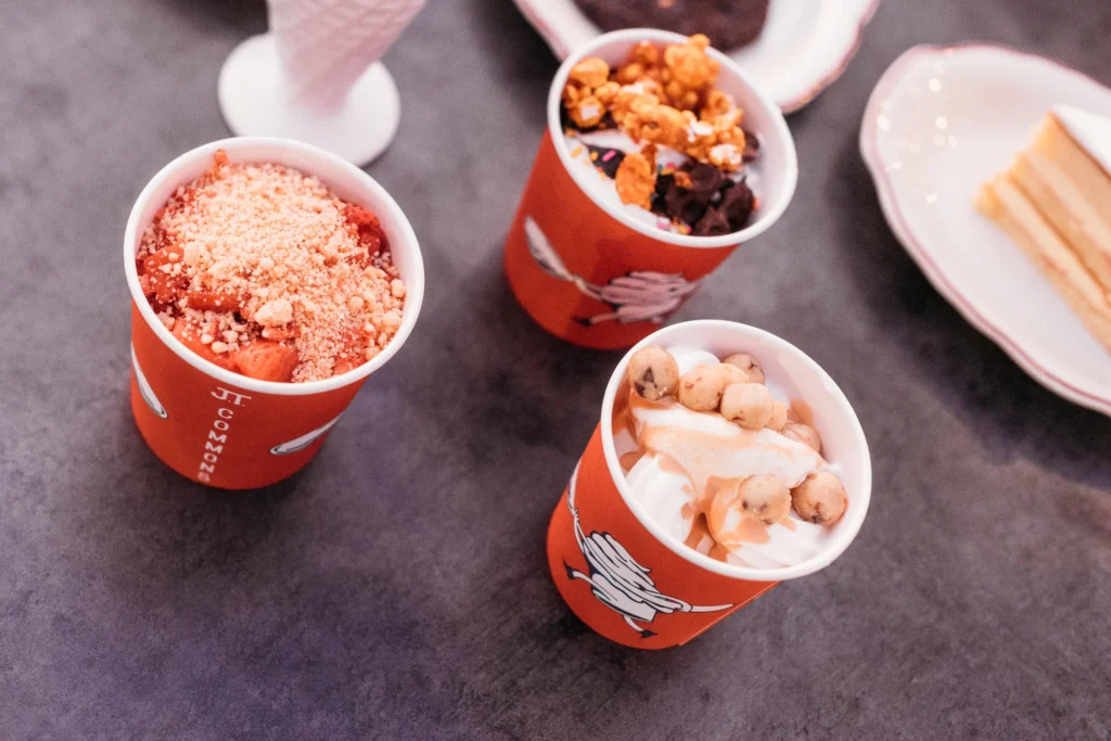An overhead view of three red ice cream cups topped with various sweets.