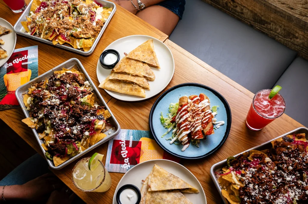 A top down view of a spread of Mexican food, including flautas, quesadillas, nachos, and drinks.
