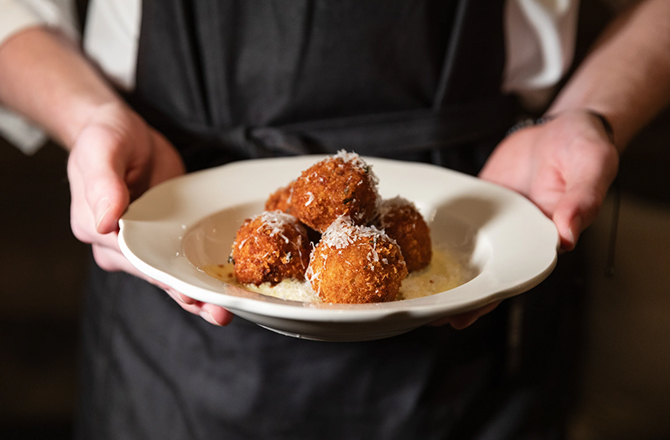 Arancini on a plate covered in cheese