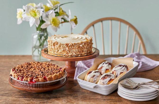 Cherry pie, coconut cake, and tray of cinnamon buns on a brightly lit table